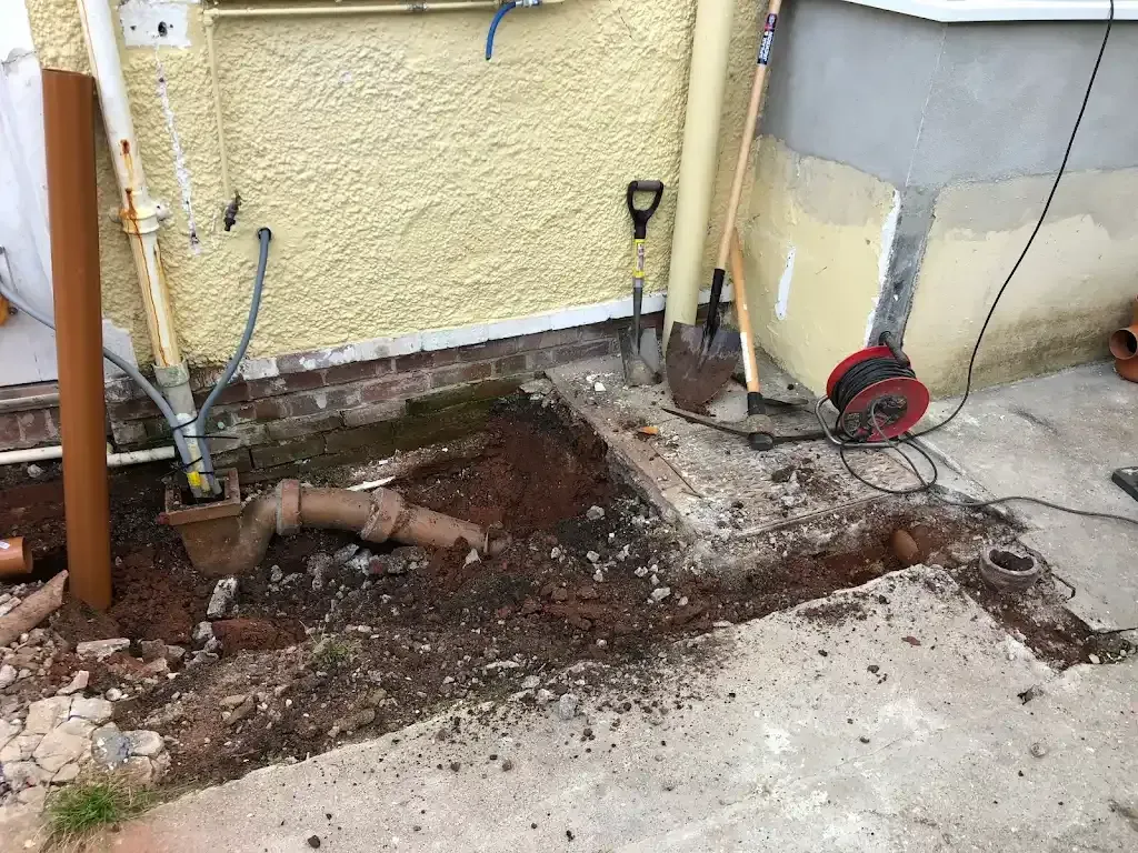 Excavated drain pipe area with tools for drainage access or repair