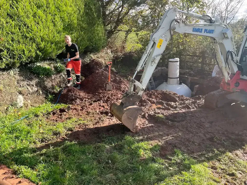Drainage worker and excavator at a site with a septic tank