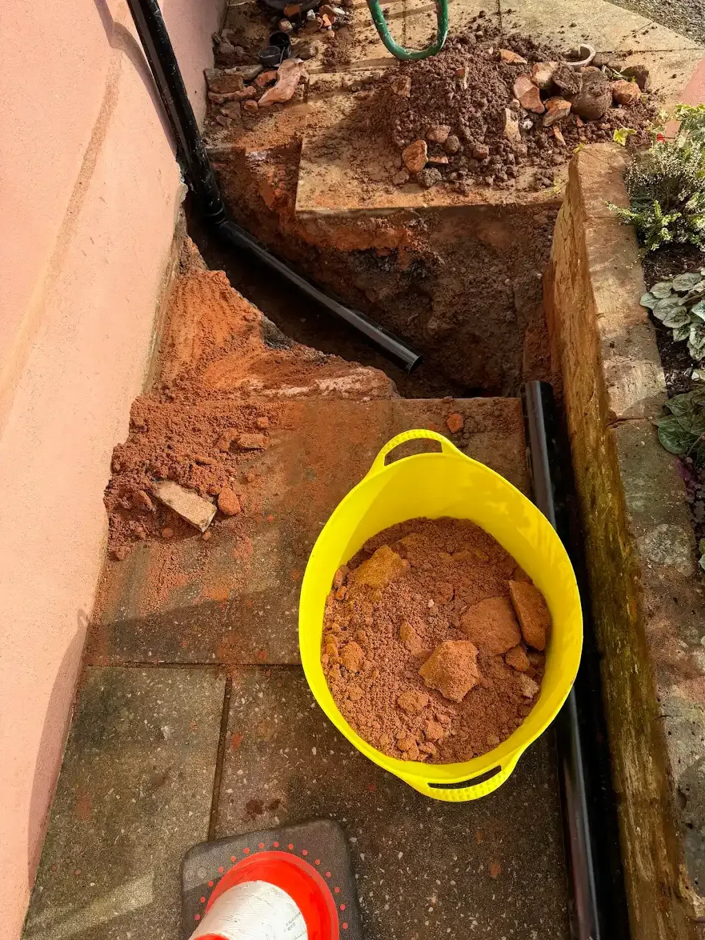 Excavated trench showing removed concrete rubble and a drain pipe during drainage access work by MJ Drains.