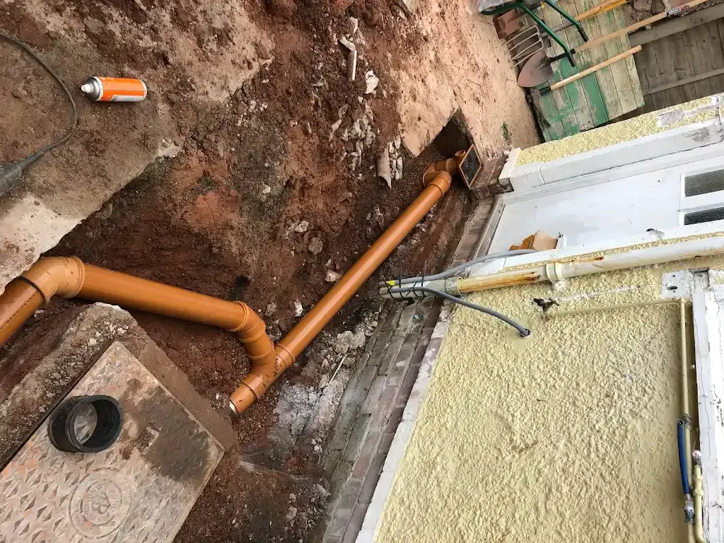 Drainage pipes installed during foundation drainage work near a property in Devon.