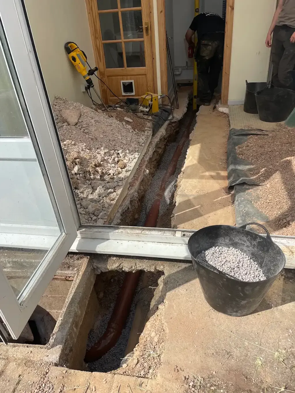 Concrete removal for drain access showing excavated trench and drainage pipes