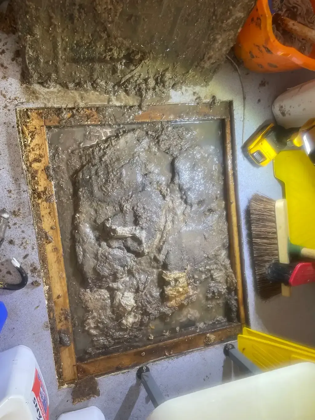 Severely blocked drain access point with mud and water.